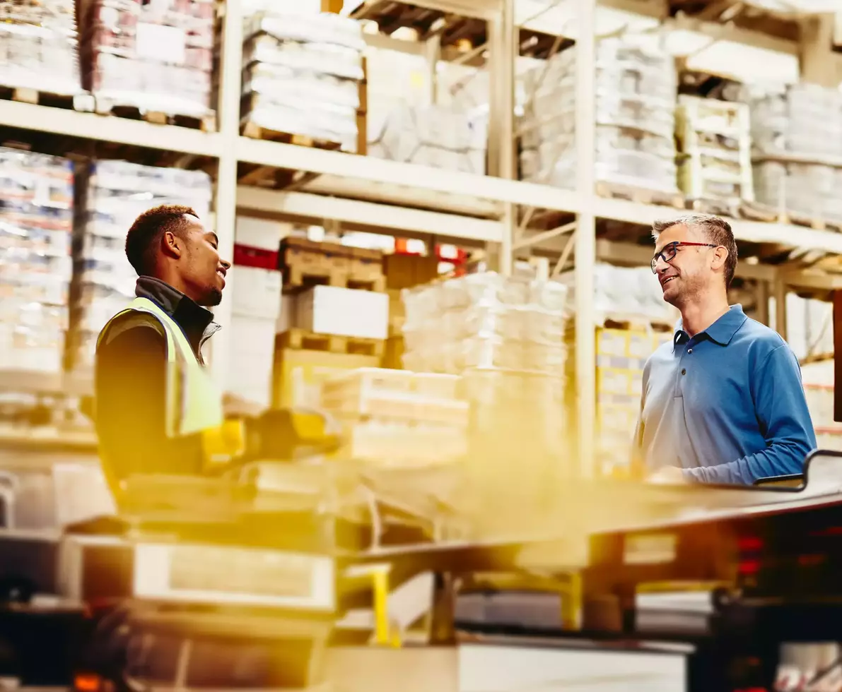 Two male working/having a conversation in a warehouse
