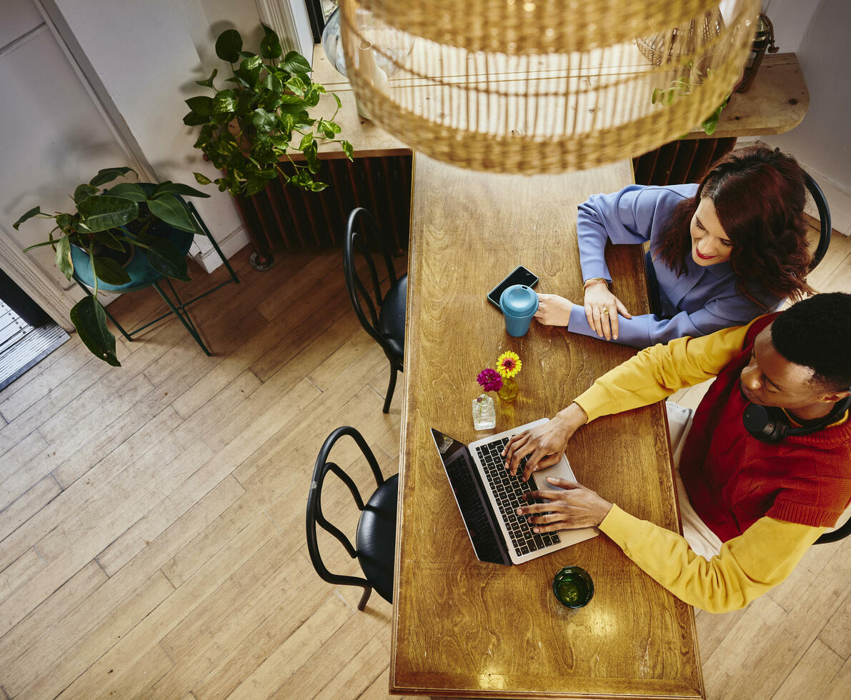 Bird view of a female and male working on a laptop at a table Bird view of a female and male working on a laptop at a table